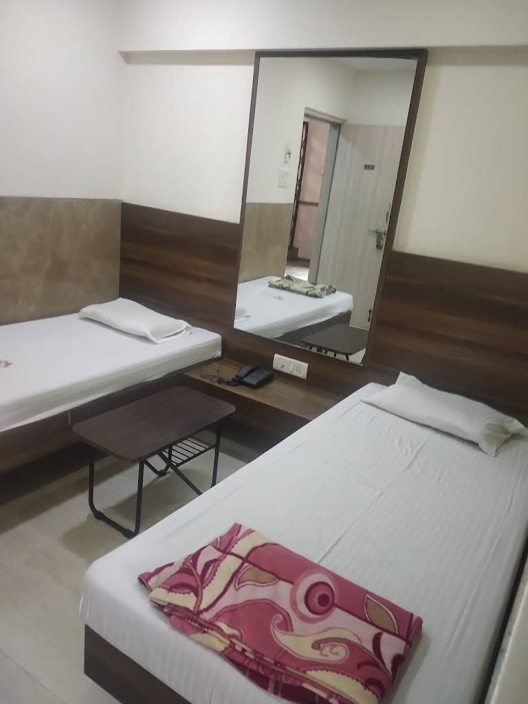 A room at the Bhavan with two beds, a table and a mirror